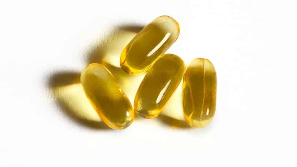 Four yellow capsules sit on a white surface.
