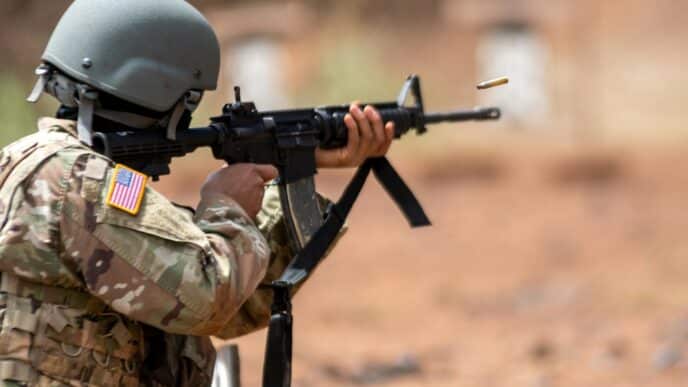 man in green and brown camouflage uniform holding rifle